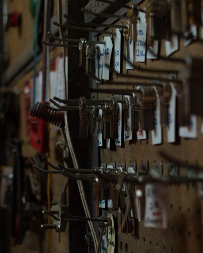 A collection of keys and locksmith tools hanging on a wall in a workshop