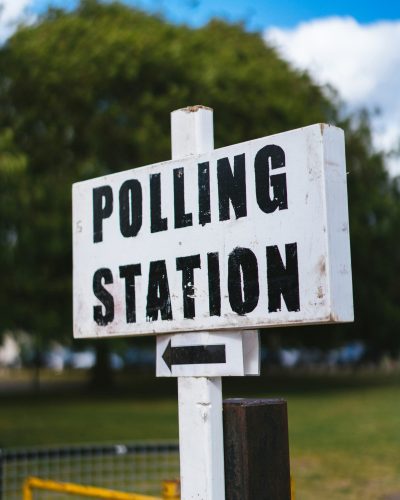 A white wooden sign that reads "polling station" in black letters.